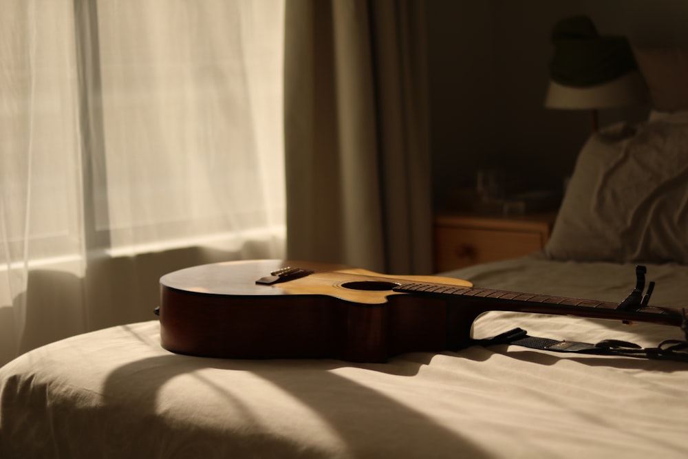 a guitar laying on top of a bed next to a window