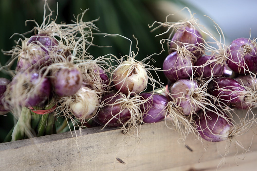 a bunch of purple onions sitting on top of a wooden box