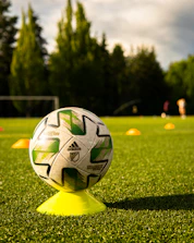 Close-up of a high-quality football and training cones on a green grass field.