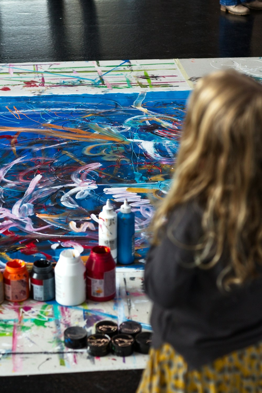 a woman sitting at a table with a painting on it