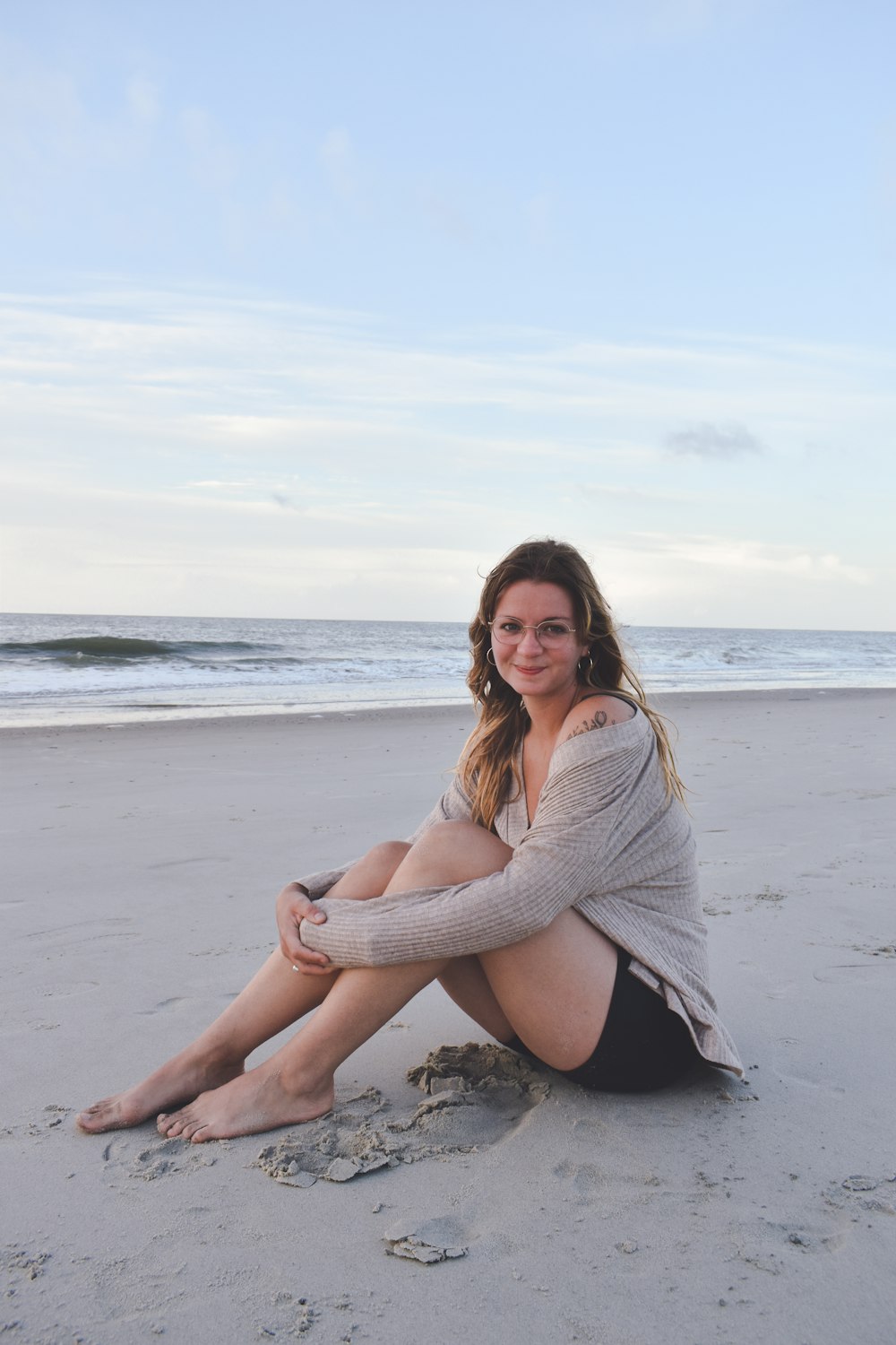 Una mujer sentada en la playa con las piernas cruzadas