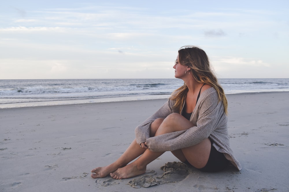 Eine Frau sitzt an einem Strand am Meer