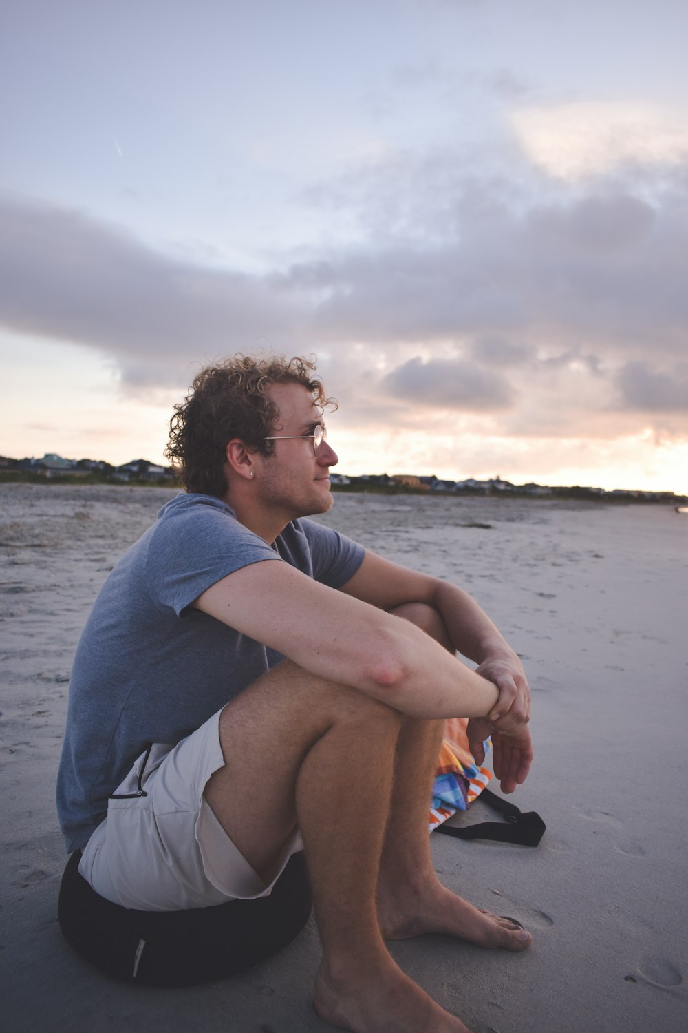 a man sitting on a beach next to a kite