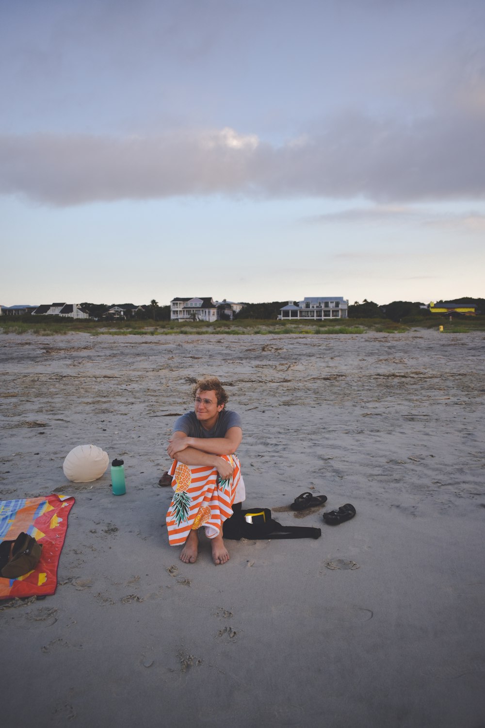 a woman sitting on a beach next to a ball