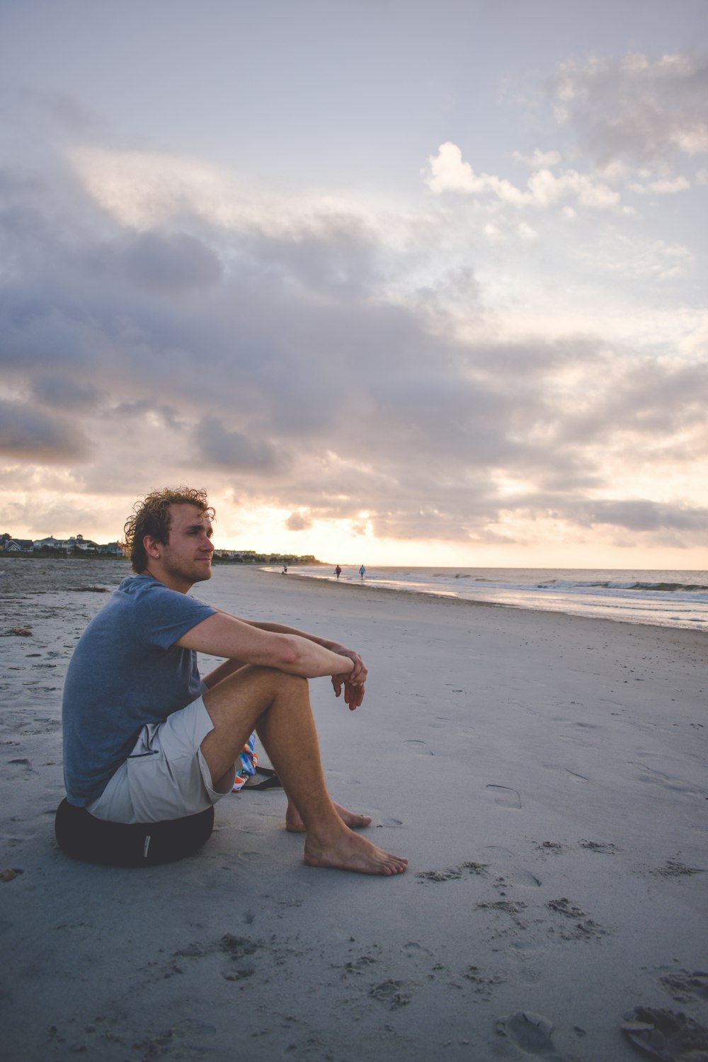 a man sitting on a beach next to the ocean