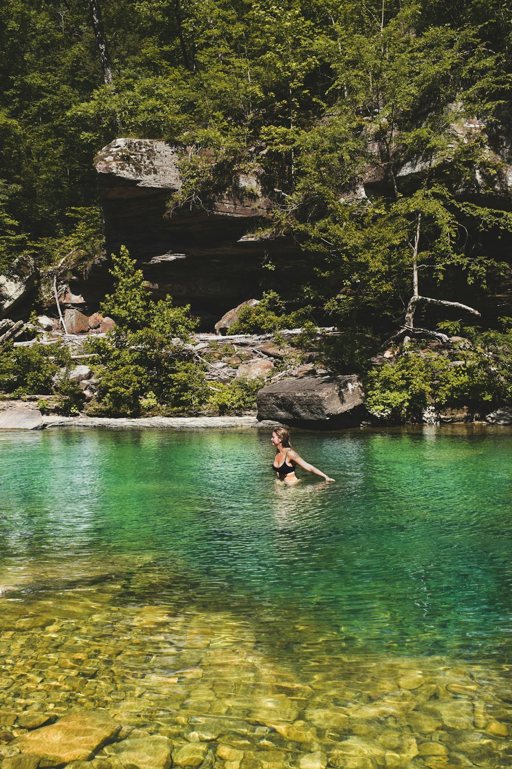 a person swimming in a lake surrounded by trees