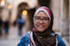 a woman wearing glasses and a scarf on a street