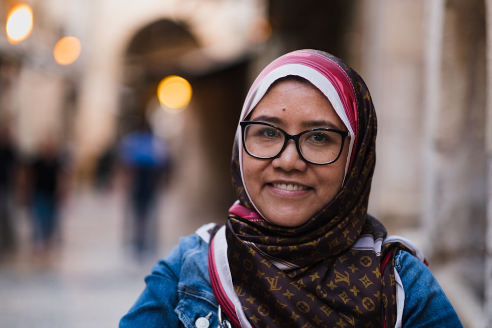 a woman wearing glasses and a scarf on a street