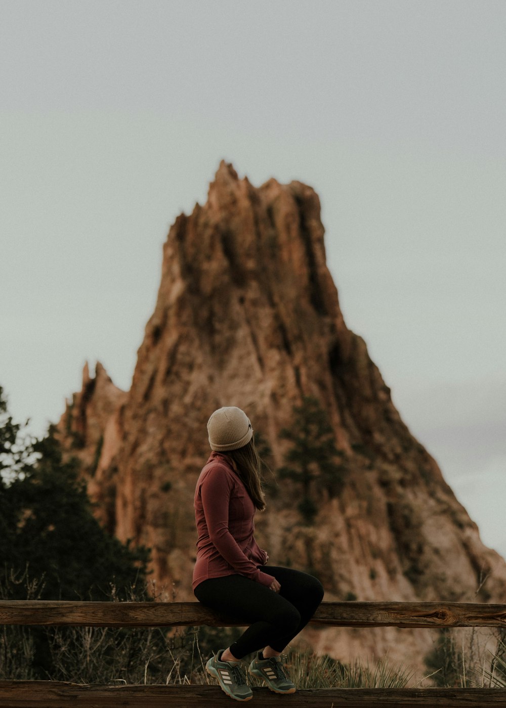 a woman sitting on a bench in front of a mountain