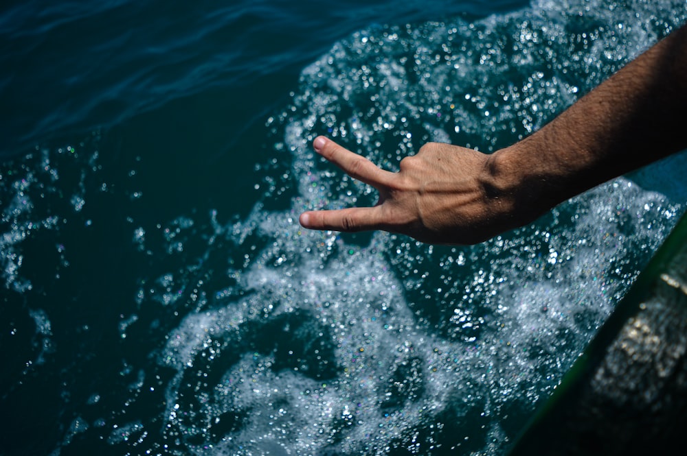 a hand reaching out to the water from a boat