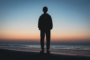 a person standing on a beach at sunset