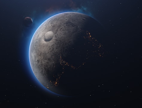 A celestial scene featuring a planet with a textured, cratered surface. The planet's edges are illuminated with a blue glow, highlighting a partial view of illuminated patterns resembling city lights. Another smaller celestial body is visible at a distance, adding depth to the space scene.