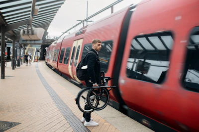 a man standing next to a train holding a bike