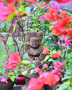 a statue in a garden surrounded by flowers