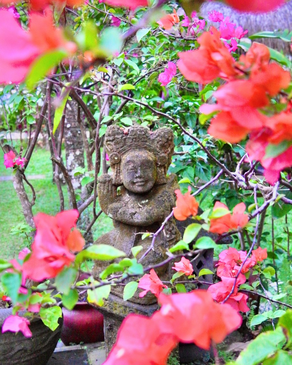 a statue in a garden surrounded by flowers