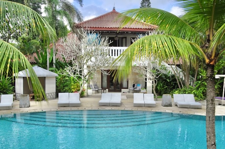 a swimming pool surrounded by palm trees and chairs