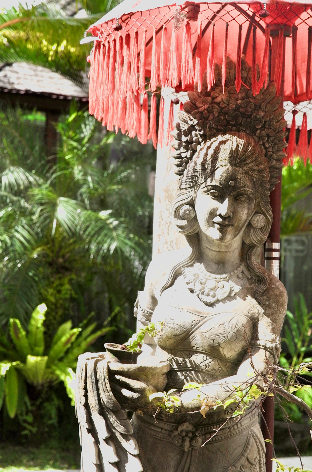 a statue of a woman holding a basket under a red umbrella