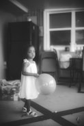 a little girl holding a balloon in a room