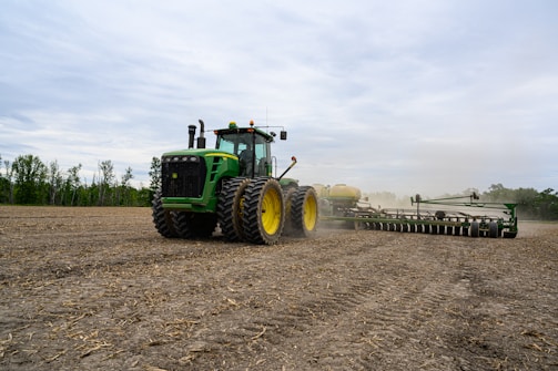 a tractor pulling a plow behind it on a farm