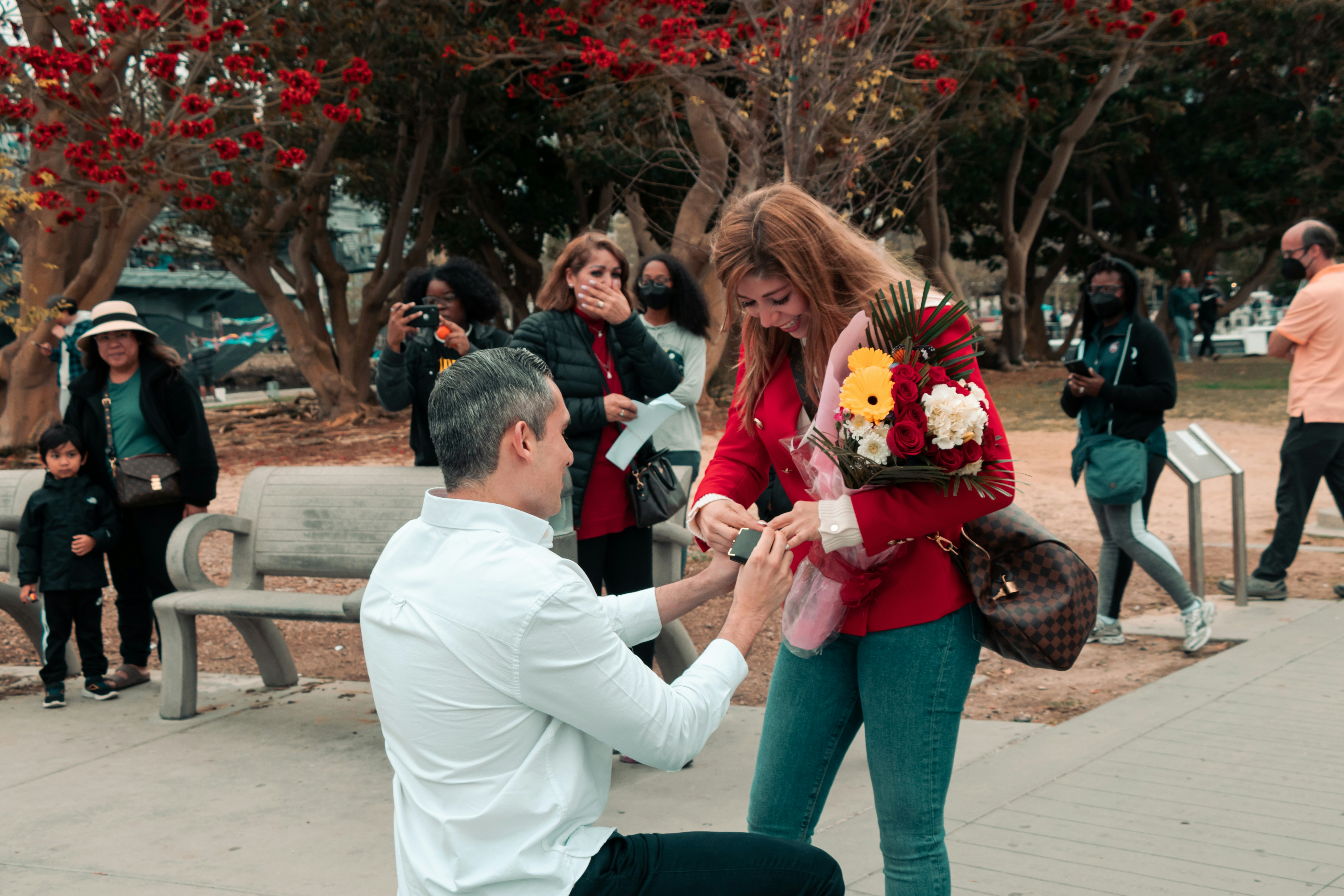 a man kneeling down next to a woman on a bench