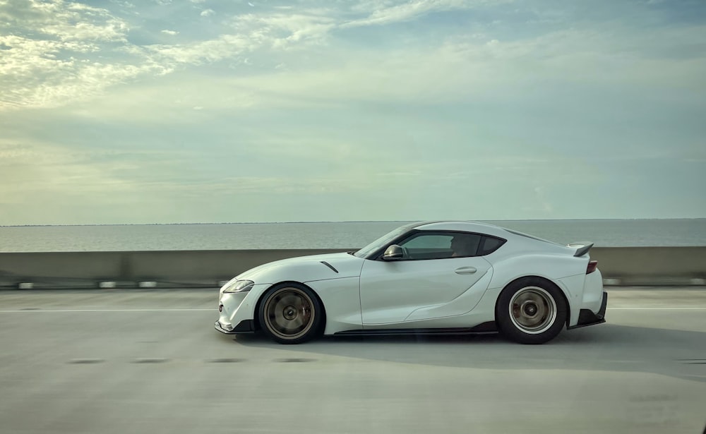 a white sports car driving down a road