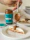 A spoonful of Dattera walnut date spread held above a slice of bread with walnut halves scattered nearby