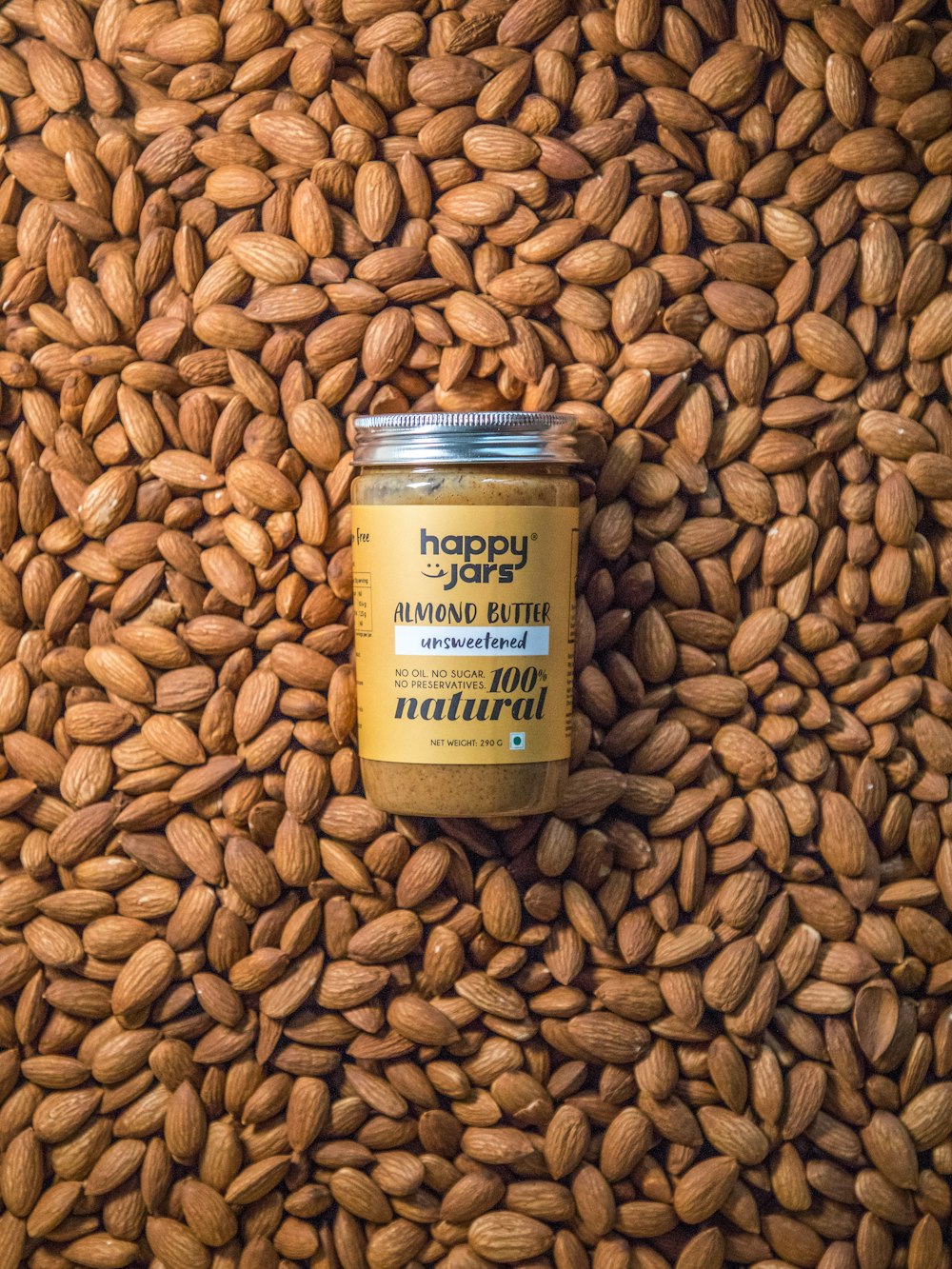 a jar of almond butter sitting on top of a pile of nuts