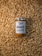 A jar of peanut butter labeled 'Happy Jars' and '100% natural' is centered on a large pile of unshelled peanuts. The design of the jar emphasizes its natural and preservative-free qualities.