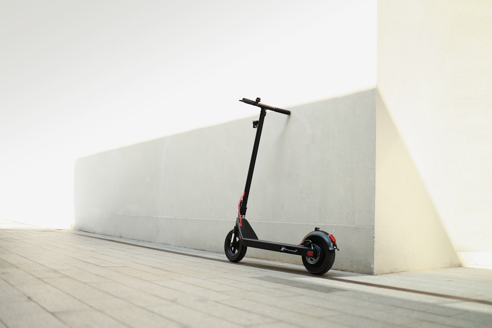 uma scooter estacionada ao lado de uma parede em uma calçada