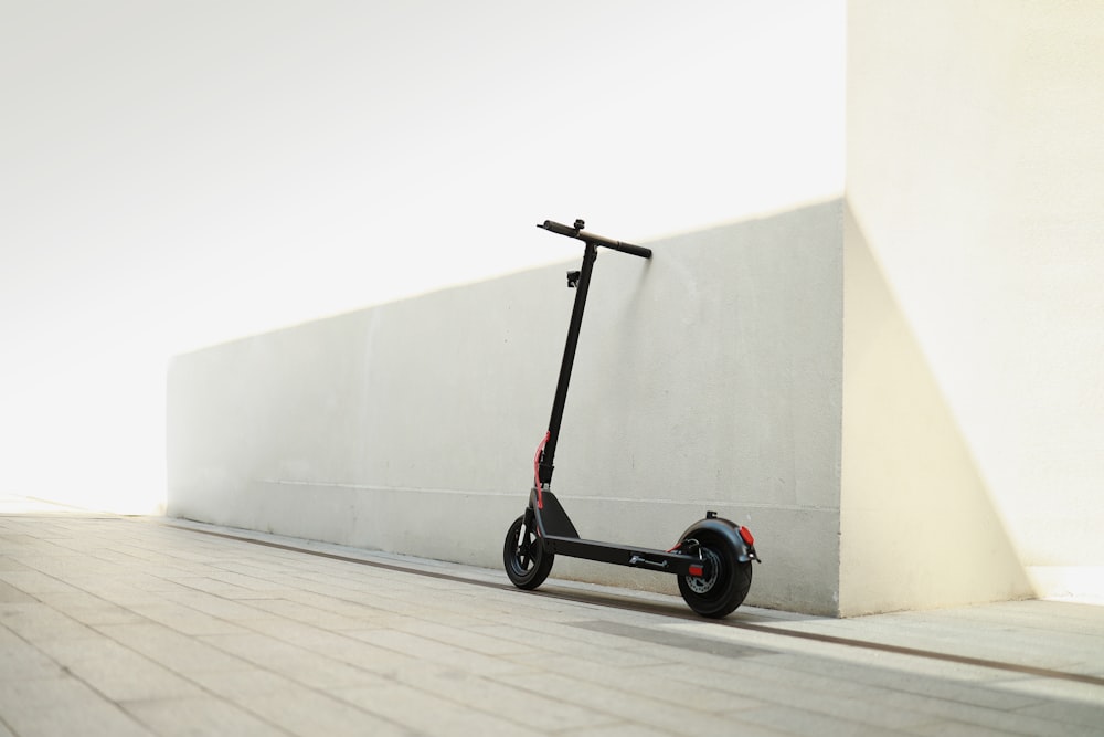 a scooter parked next to a wall on a sidewalk