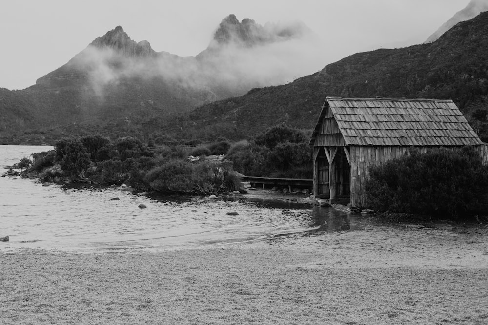 a black and white photo of a hut on a beach