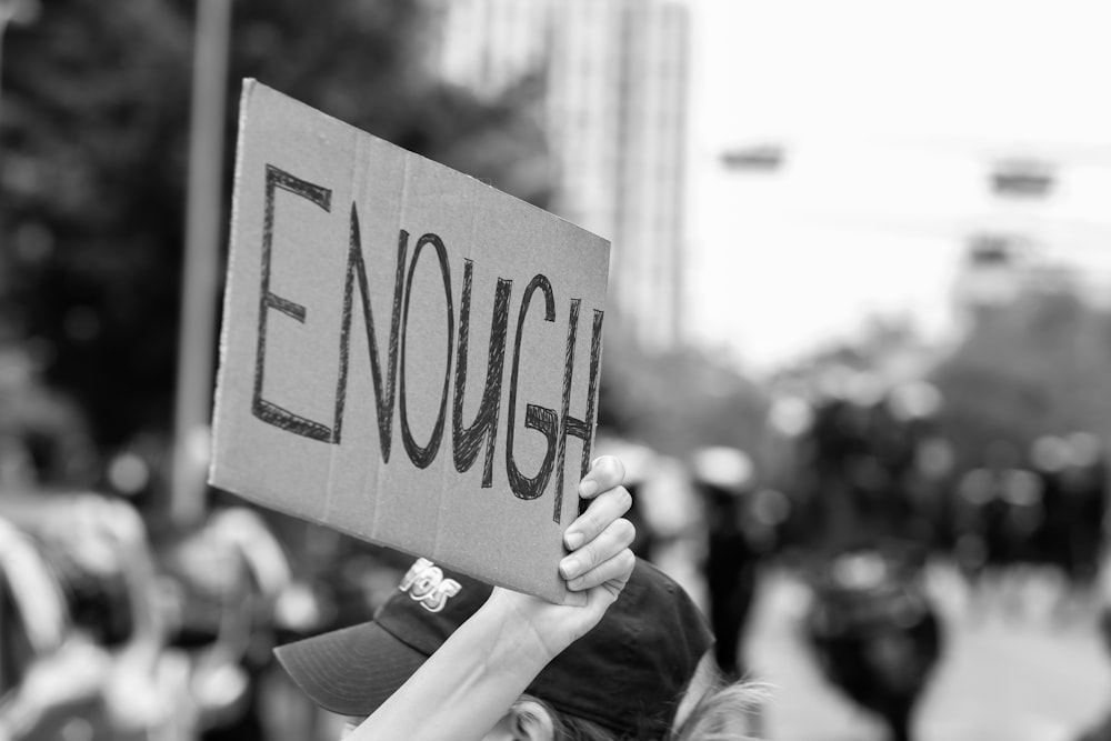 a person holding a sign that says enough