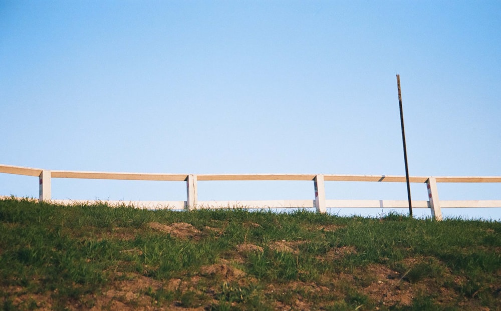 a white fence sitting on top of a lush green hillside