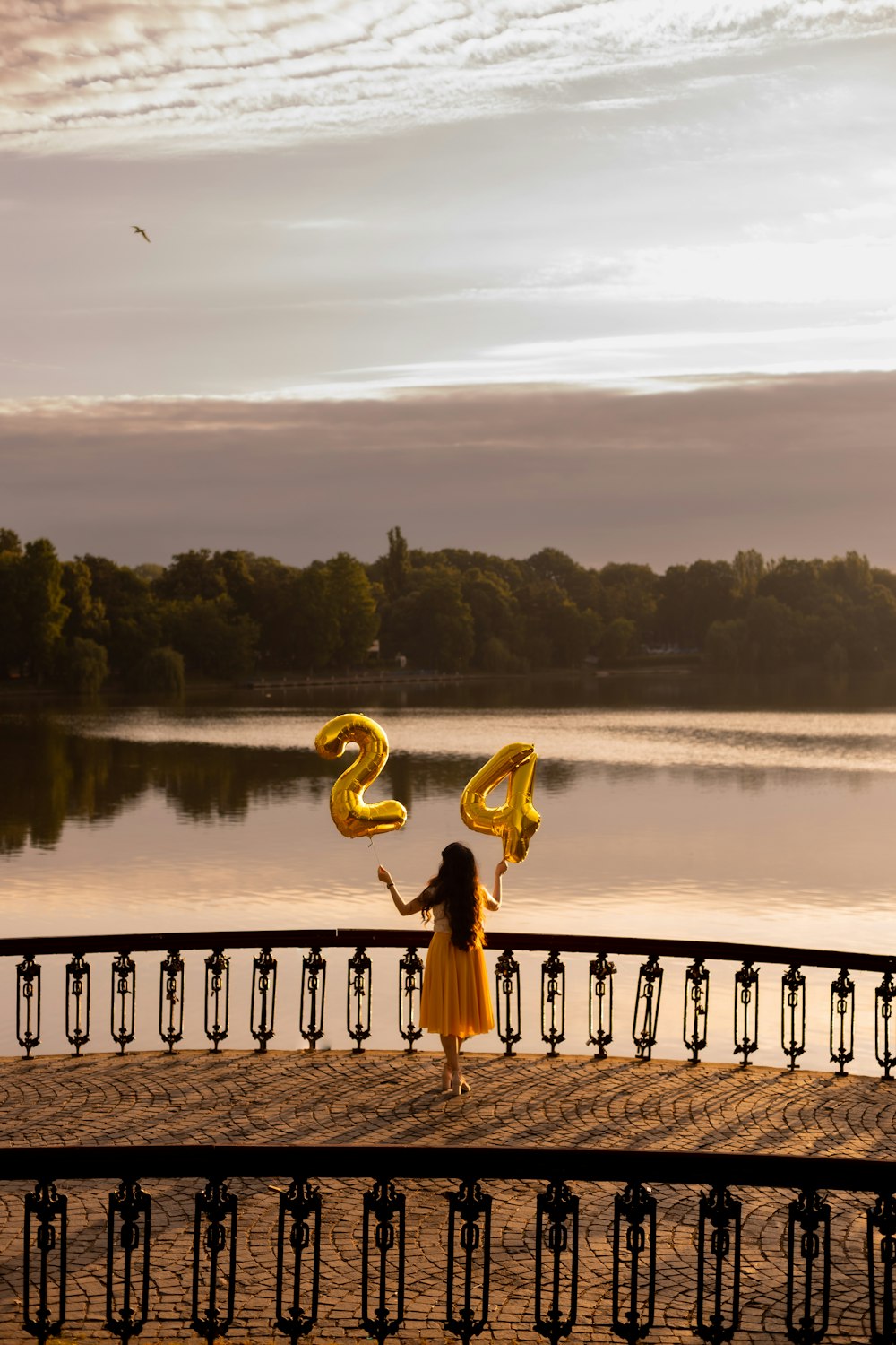 a girl in a yellow dress holding two yellow balloons