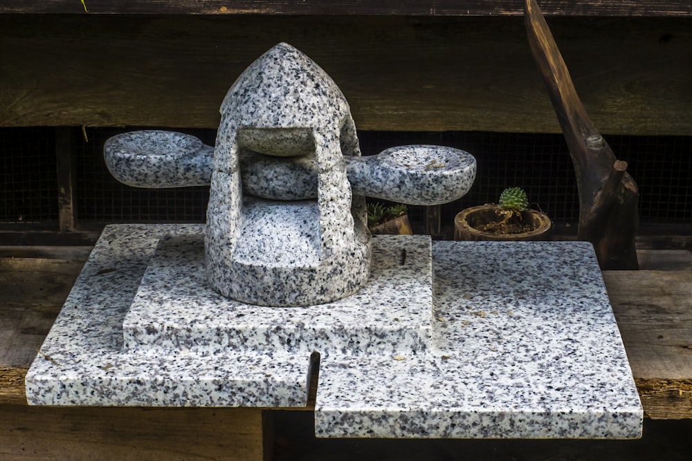 a stone sculpture of a chair and a potted plant