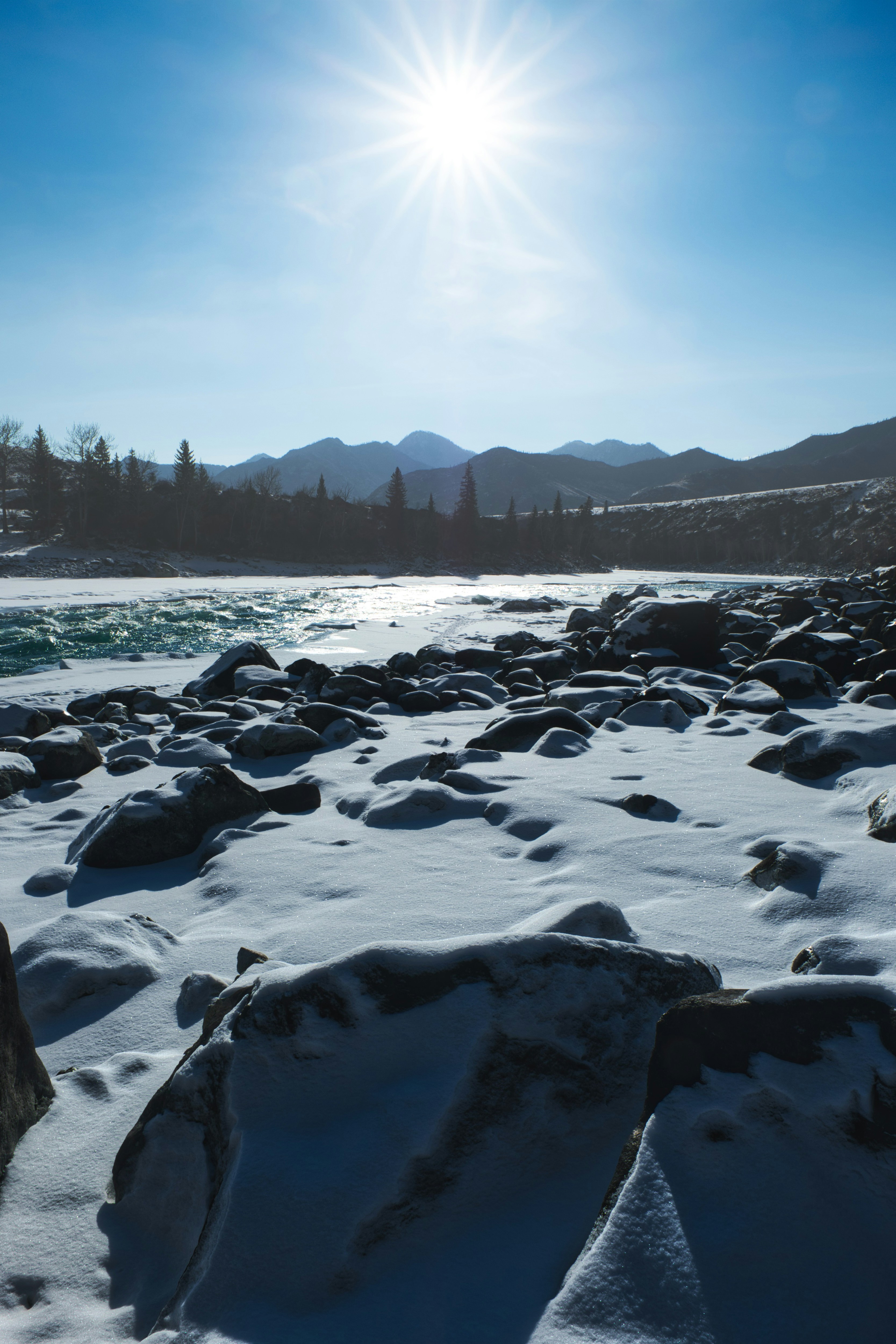 the sun is shining over a snowy river