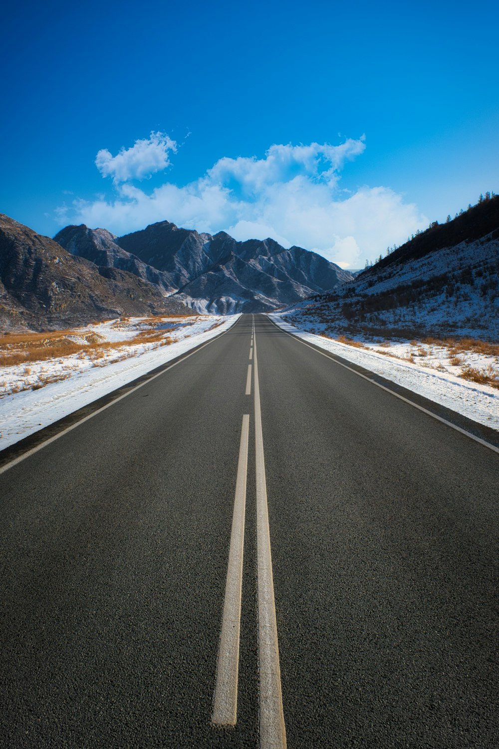 an empty road in the middle of a mountain range