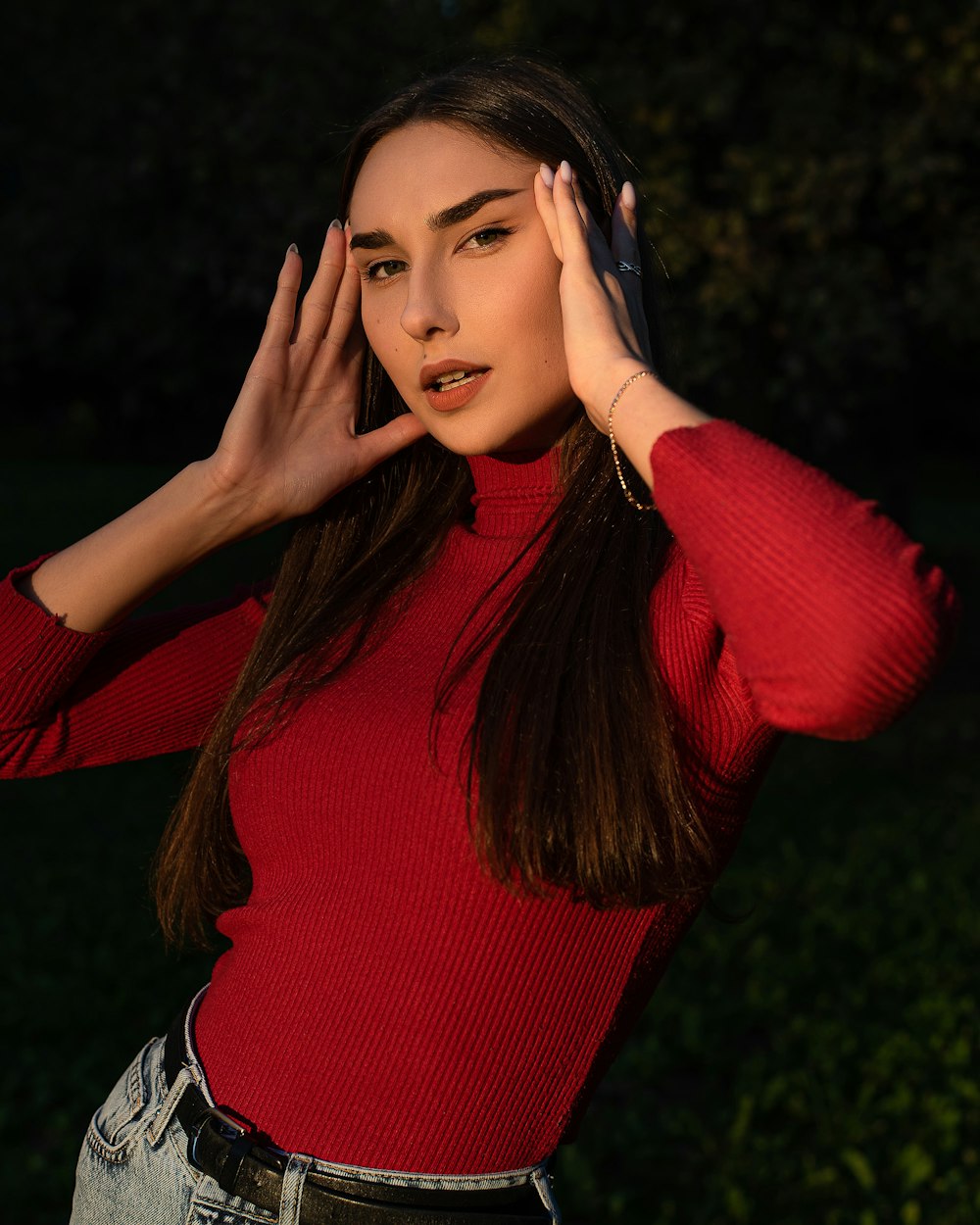 a woman in a red shirt is holding her hands up to her ear