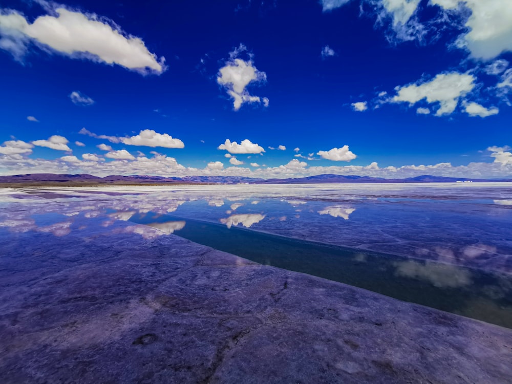 a large body of water sitting under a cloudy blue sky