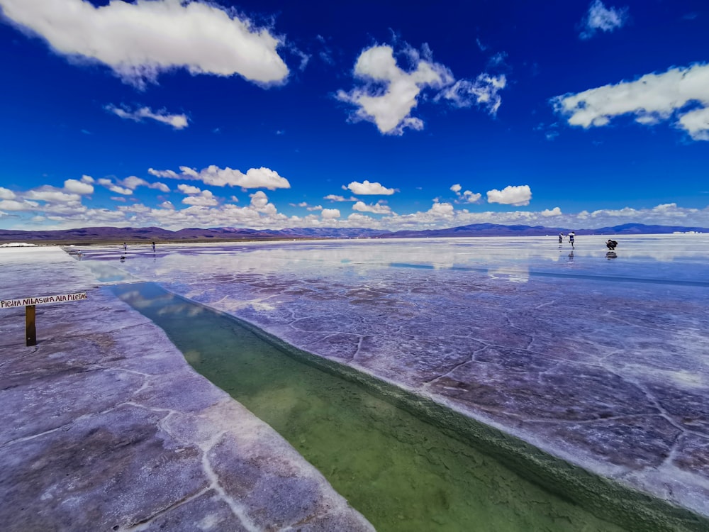 a large body of water surrounded by a blue sky