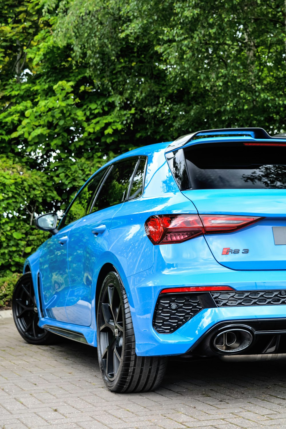 a blue car parked in front of some trees