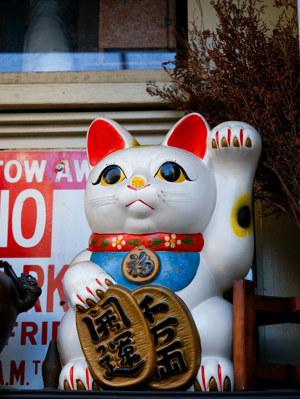 a white cat statue sitting on top of a shelf