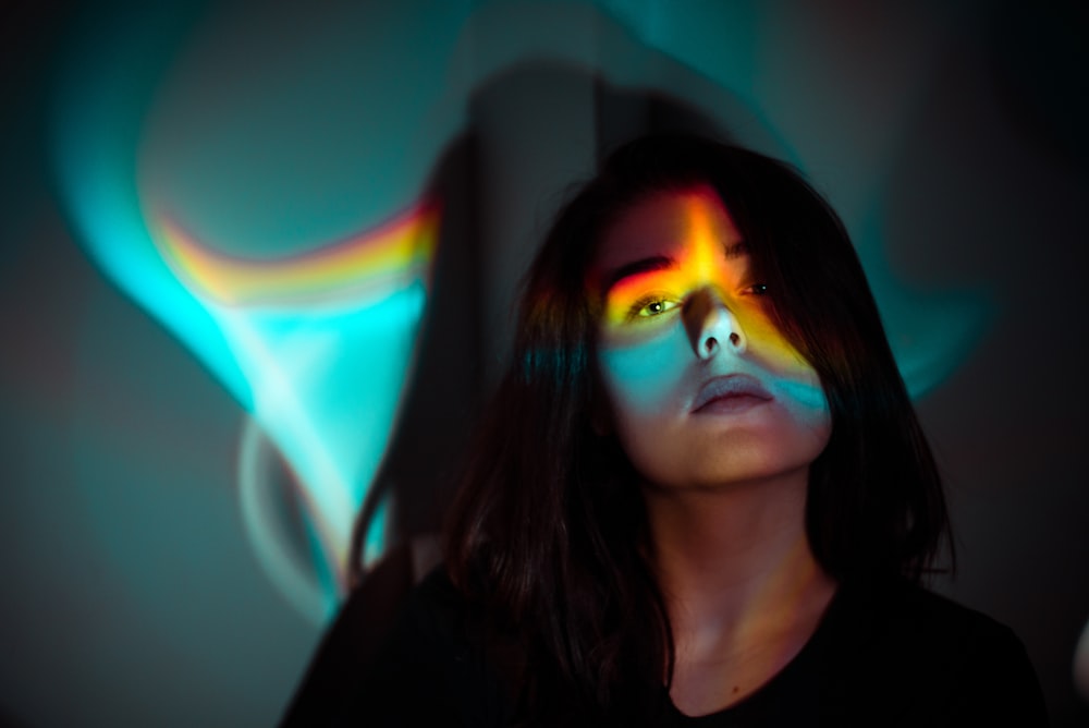 a woman with a rainbow painted face in a dark room
