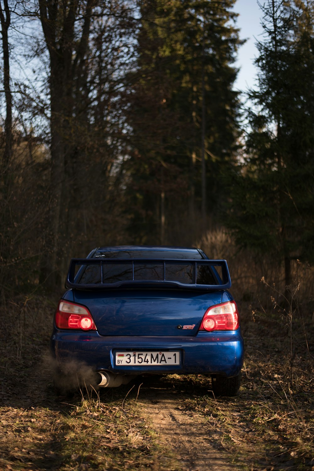 a blue car driving down a dirt road
