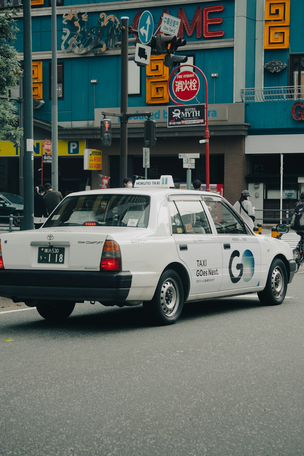 a white taxi cab driving down a street next to a tall building