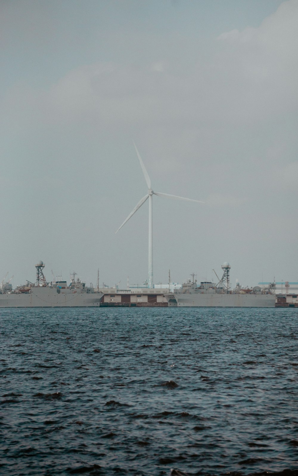 a large ship in the water with a wind turbine in the background