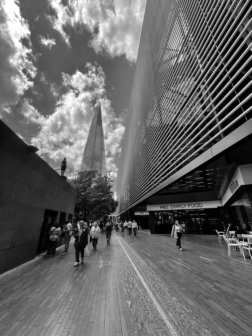 a black and white photo of people walking on a boardwalk