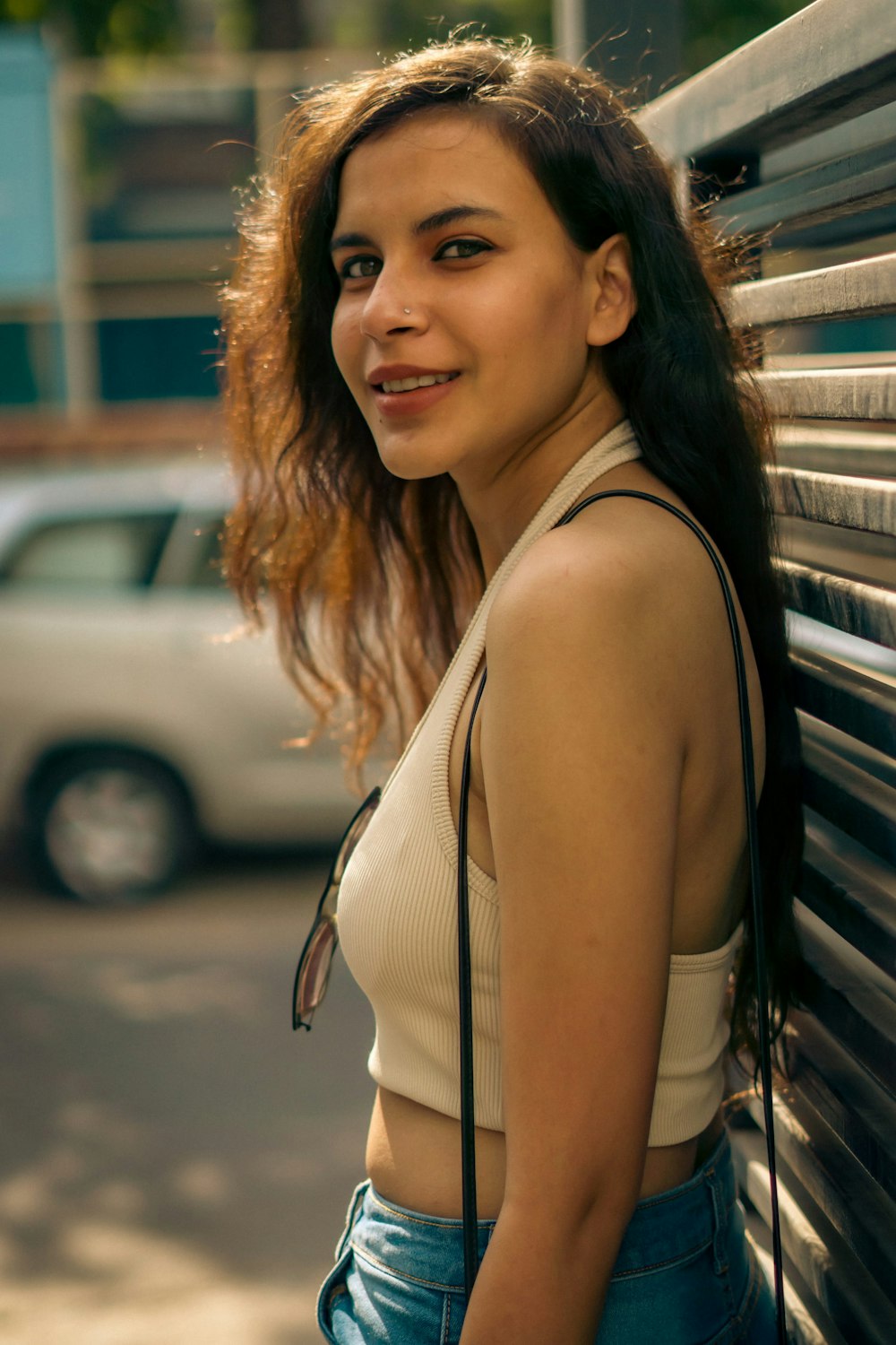 a woman leaning against a wall with a purse on her shoulder