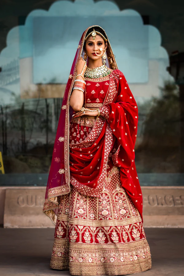 Bride in a red lehenga standing in a palace hall