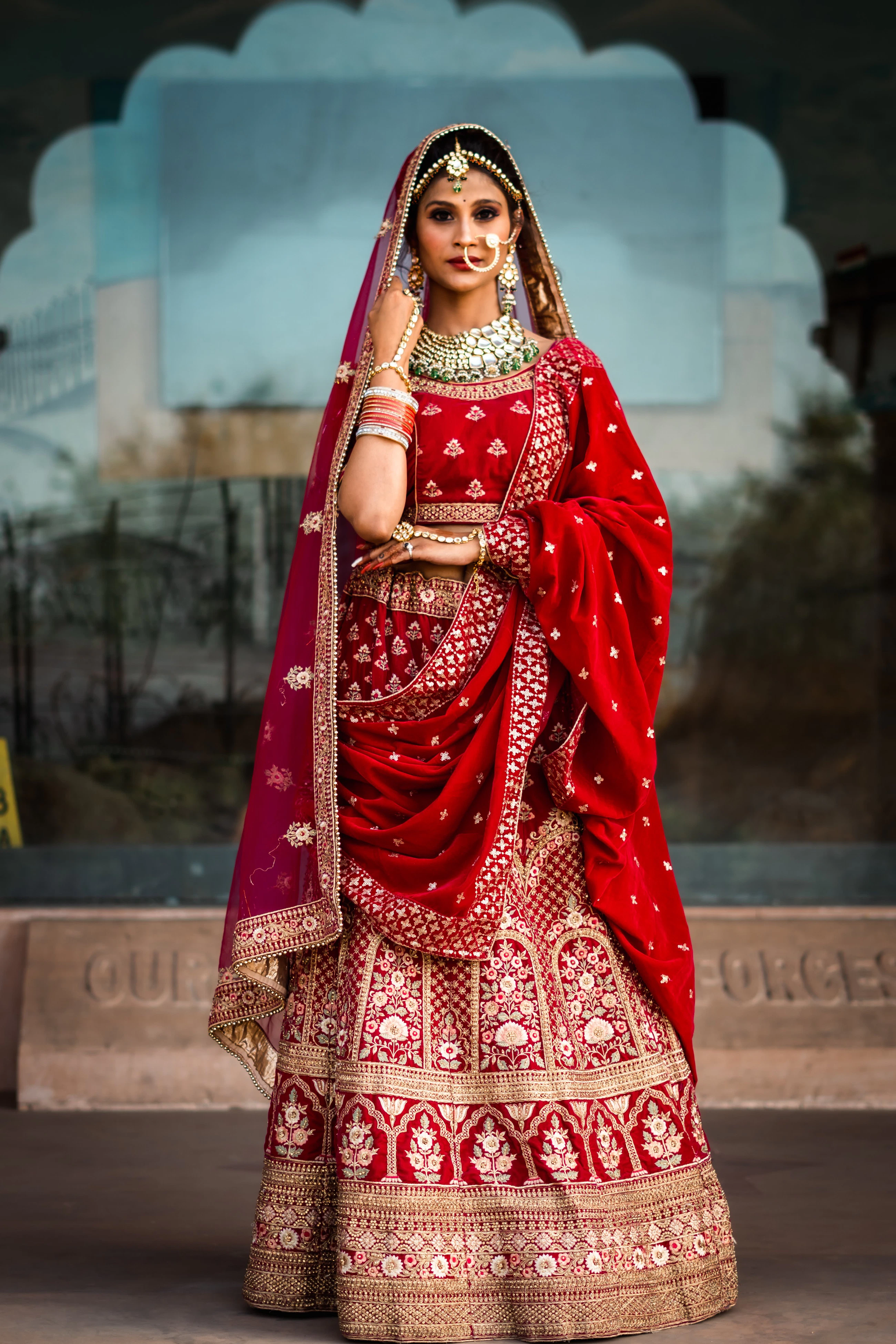Model wearing an elaborate red and gold bridal jewellery set